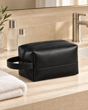 Black ALTAIR wash bag beside a bathroom sink